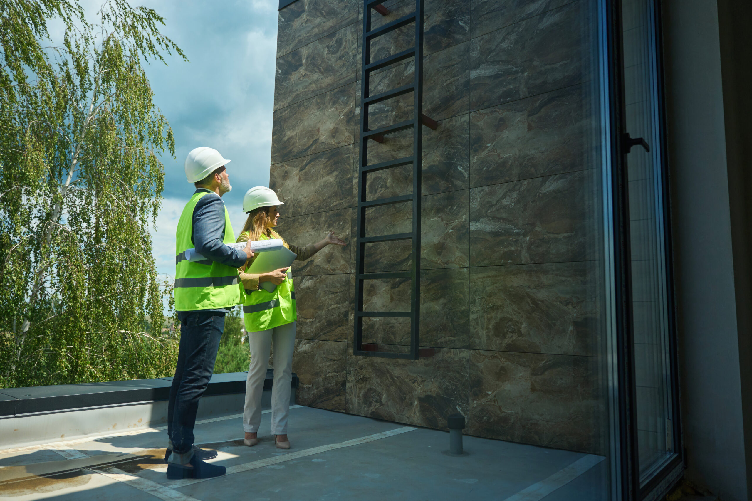 Beautiful woman realtor and adult foreman inspect balcony of house