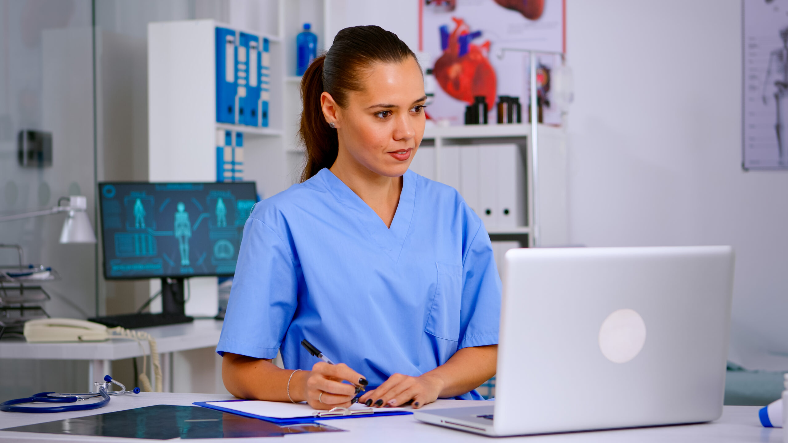 Doctor assistant in uniform working on laptop in modern hospital