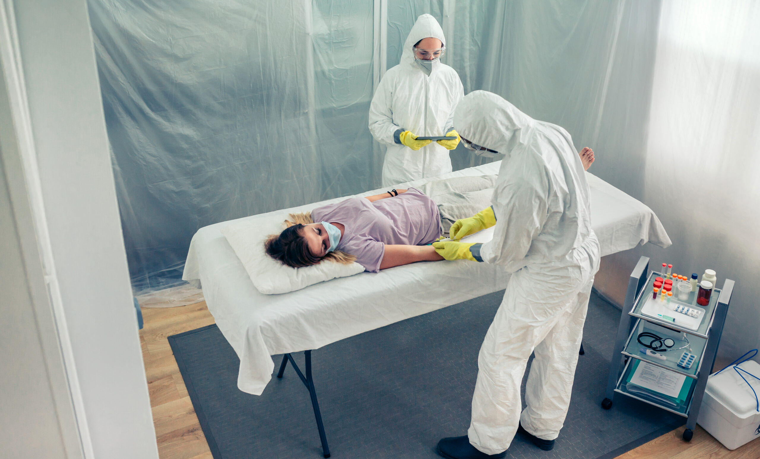Doctors taking blood sample from patient lying on a gurney