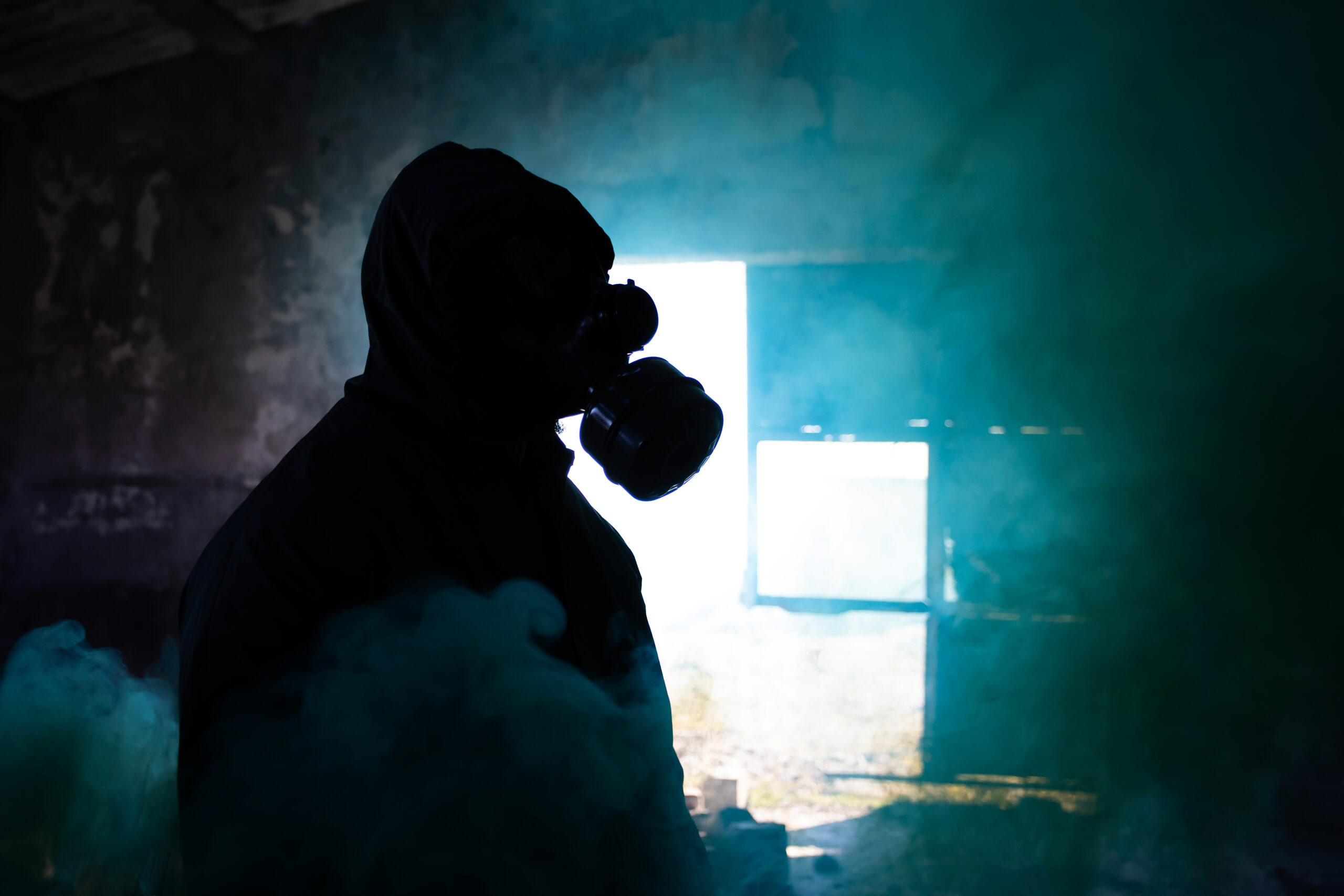 Dramatic portrait of a man wearing a gas mask in a ruined buildi
