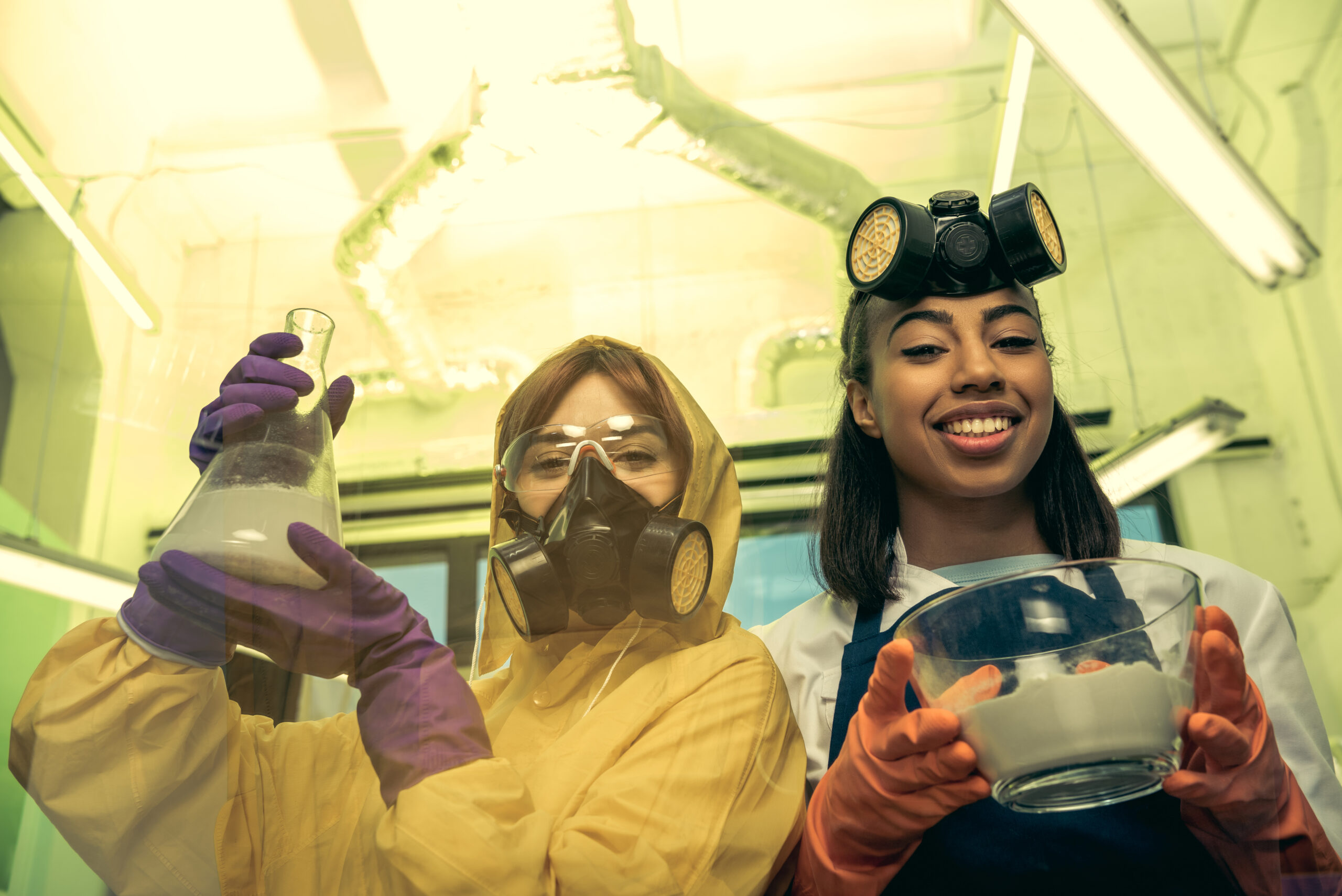 portrait of women in uniforms holding flask and bowl with reagents in laboratory, drugs concept