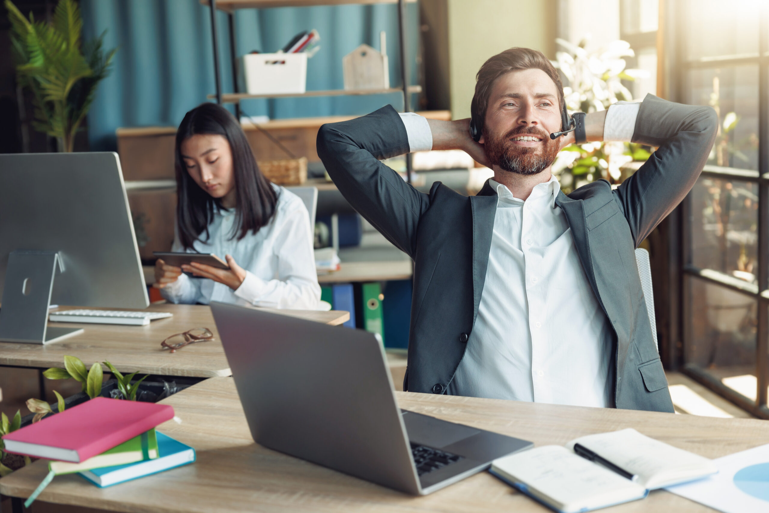 Man office worker have a rest on his workplace on background of colleague