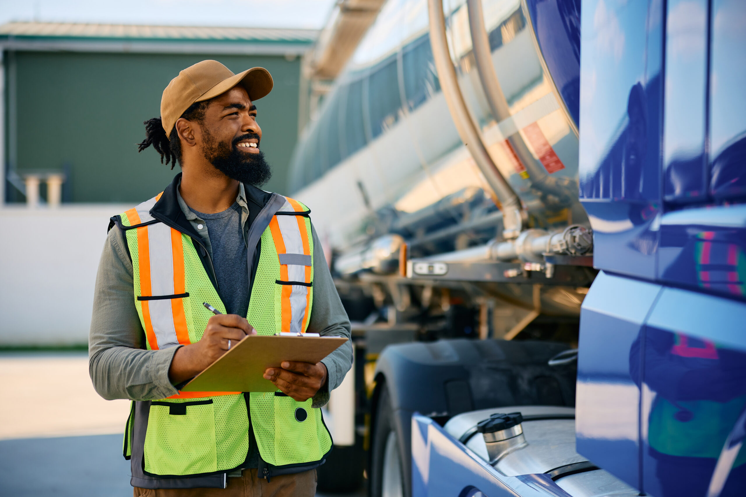 Happy black freight transportation dispatcher examining a truck before the ride.